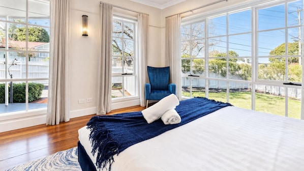 Een slaapkamer met een groot bed, een stoel en uitzicht op het omliggende landschap.