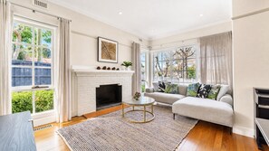 A living room with a fireplace, a sofa, a coffee table, and large windows. - The Ringwood Rambler Yard  Family Retreat (Ringwood)