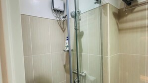 A glass-enclosed shower with a handheld showerhead, a handheld shower attachment, and a wall-mounted faucet. - Cozy Scandinavian-inspired Condo With Balcony Facing SM Mall of Asia (Pasay)
