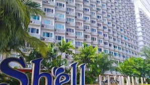 A high-rise residential building with balconies and a sign that reads 'Shell.' - Cozy Scandinavian-inspired Condo With Balcony Facing SM Mall of Asia (Pasay)