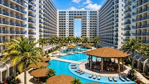 A resort with a central swimming pool, lounge areas, and multiple high-rise buildings. - Cozy Scandinavian-inspired Condo With Balcony Facing SM Mall of Asia (Pasay)