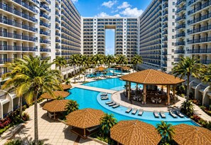 A resort with a central swimming pool, lounge areas, and multiple high-rise buildings. - Cozy Scandinavian-inspired Condo With Balcony Facing SM Mall of Asia (Pasay)