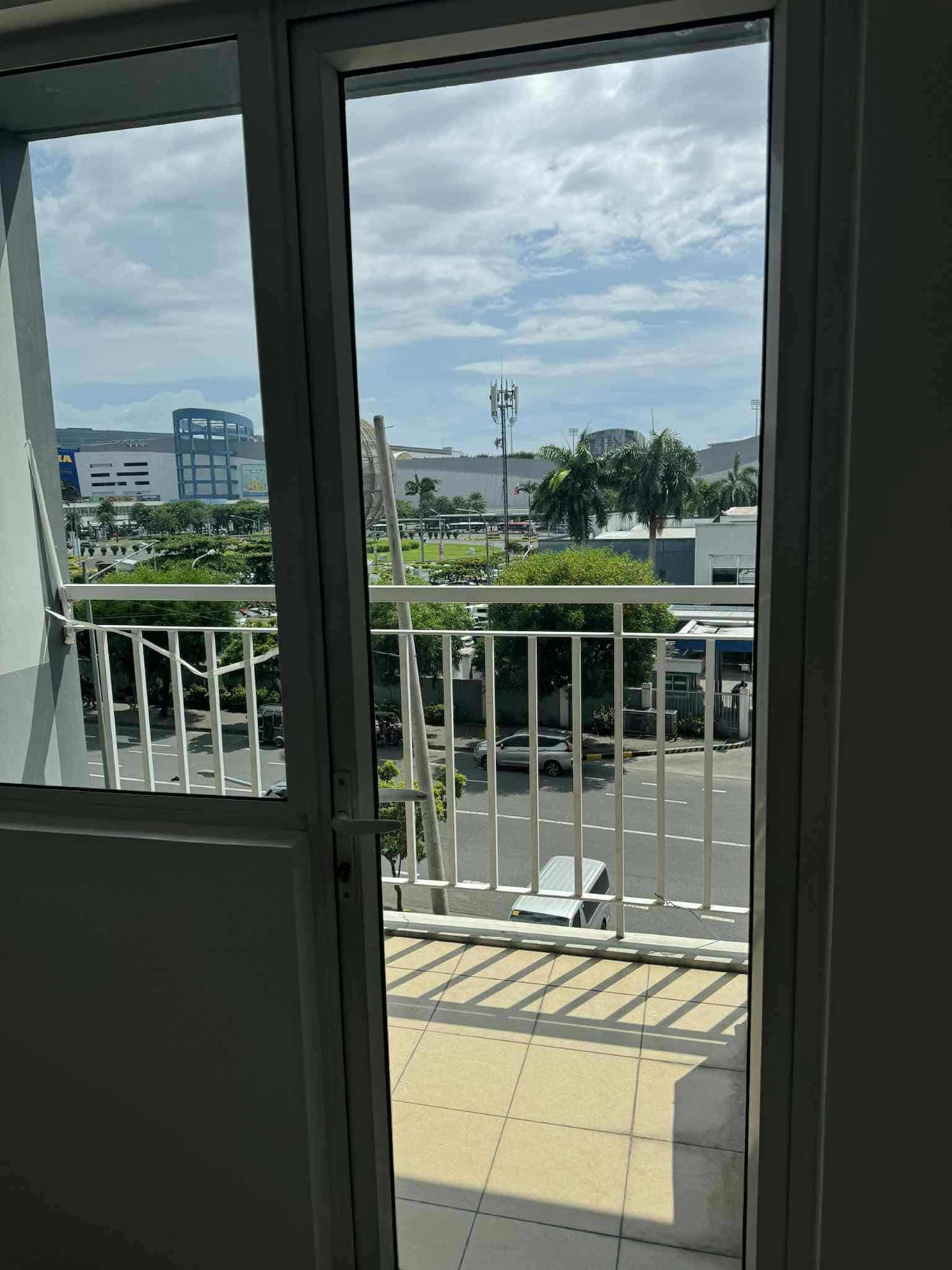 Blick vom Balkon mit Metallgeländer, klarer Himmel und ein Parkplatz mit Fahrzeugen.