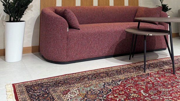 Un interior moderno con un sofá seccional, una alfombra estampada y una pared con iluminación geométrica.