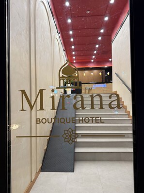 L'entrée d'un hôtel, avec un escalier menant à la réception.
