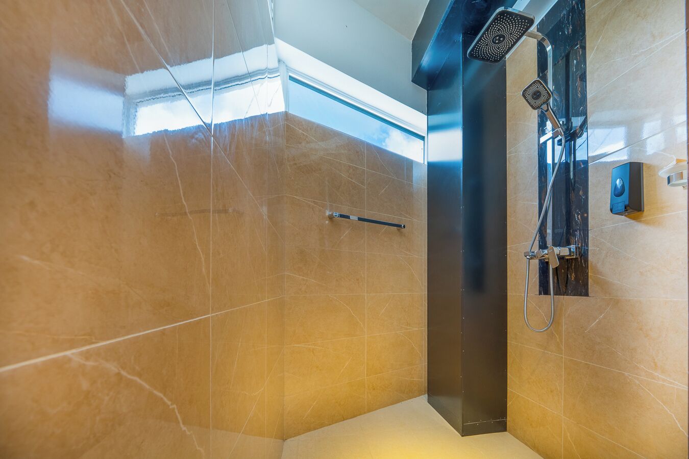A modern bathroom with a glass-enclosed shower, marble walls, and a visible towel rack.