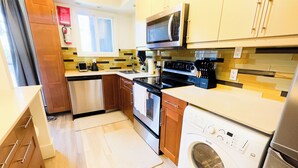 Een moderne keuken met een vaatwasser, oven, magnetron en een ingebouwde wasmachine.
