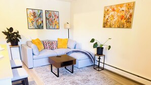 Een moderne woonkamer met een bank, salontafel en kunstwerken aan de muren.