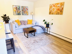 Ein stilvolles Wohnzimmer mit Sofa, Couchtisch und Bildern an den Wänden.