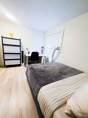 A bedroom with a bed, a desk, a chair, a radiator, and a wardrobe. - 1 Bedroom Condo - Perfect Calgary Base (Calgary)