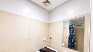Et badeværelse med toilet, vaskemaskine, vask og bruser.