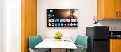 A modern kitchen with a flat-screen TV mounted on the wall displaying a streaming service interface.