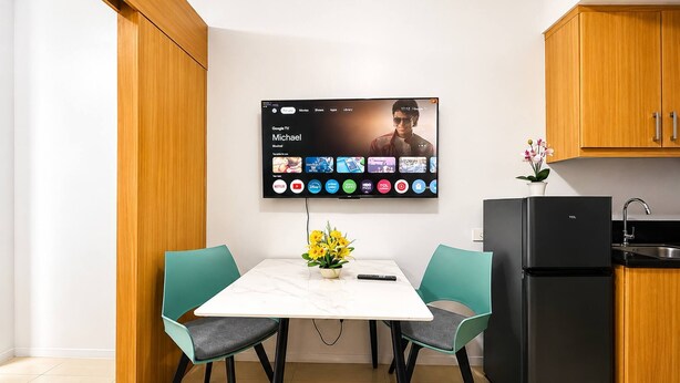Et moderne køkken med et fladskærms-tv på væggen, der viser en streamingtjenestes brugerflade.
