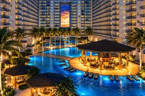 A multi-level hotel with a large indoor swimming pool, lounge areas, and a central bar. - Perky 1-bedroom Apartment in Vibrant Pasay City (Pasay)