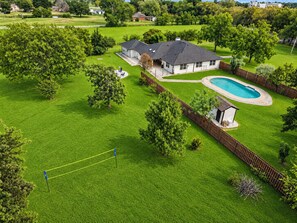 Ein Wohnhaus mit Pool, einem eingezäunten Garten und einem Dach in dunkler Farbe.