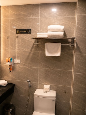Ein Badezimmer mit Toilette, einem Handtuchhalter mit Handtüchern, einem Handtrockner und einem Schild, das einen 50%-igen Rabatt anzeigt.