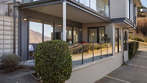 A modern building with a covered entrance, large windows, and a well-maintained hedge. - Lakeview on Goldrush (Queenstown)