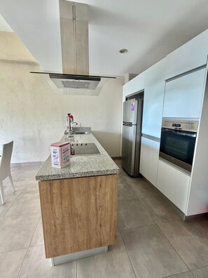 A modern kitchen with a granite countertop, stainless steel appliances, and white cabinetry. - Beautiful, relaxing and convenient in Nuevo Vallarta! (Nuevo Nayarit)