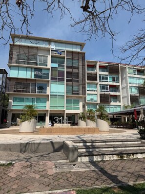 A multi-story building with a modern architectural design, featuring large windows and a ground-level entrance. - Beautiful, relaxing and convenient in Nuevo Vallarta! (Nuevo Nayarit)