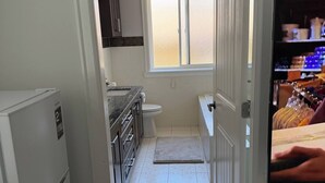 A narrow kitchen with a refrigerator, a sink, and a window.
