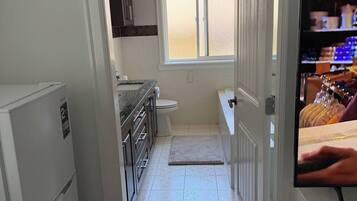 A narrow kitchen with a refrigerator, a sink, and a window.