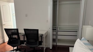 A hotel room with a bed, two chairs, a desk, and a wardrobe.