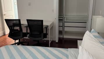 A hotel room with a bed, two chairs, a desk, and a wardrobe.