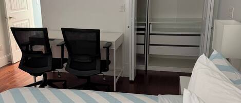 Habitación de hotel con una cama, dos sillas, un escritorio y un armario.