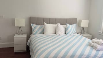 A bedroom with a bed, two bedside tables, a ceiling fan, and a window.