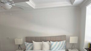A bedroom with a bed, two bedside tables, a ceiling fan, and a window.