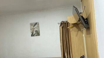 Habitación de hotel con cama, escritorio, silla, televisor montado en la pared y una pequeña planta en maceta.