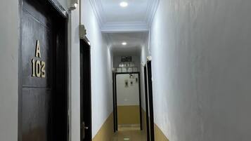 Un pasillo con una puerta identificada con 'A 103' que da a una habitación con cama y ventana.