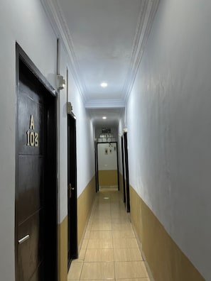 A corridor with a door labeled 'A 103' leading to a room with a bed and a window.