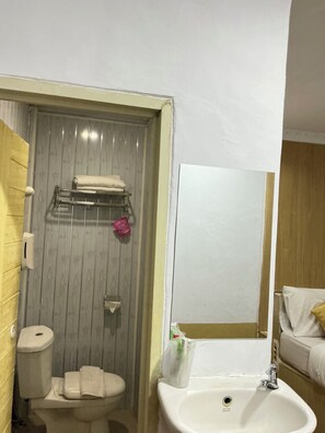 A bathroom with a toilet, sink, and a shower area. - My Home Inn Cibubur (Bekasi)