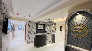 En hotellobby med väggar klädda i marmor, en receptionsdisk och en skylt med text.