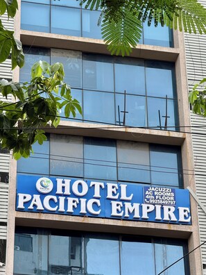 Placa de hotel com a inscrição 'PACIFIC EMPIRE' e 'QUARTOS COM JACUZZI, 4º ANDAR', juntamente com um número de telefone.