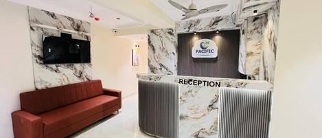 A reception area with a marble wall, a red sofa, and a reception desk labeled 'RECEPTION.'