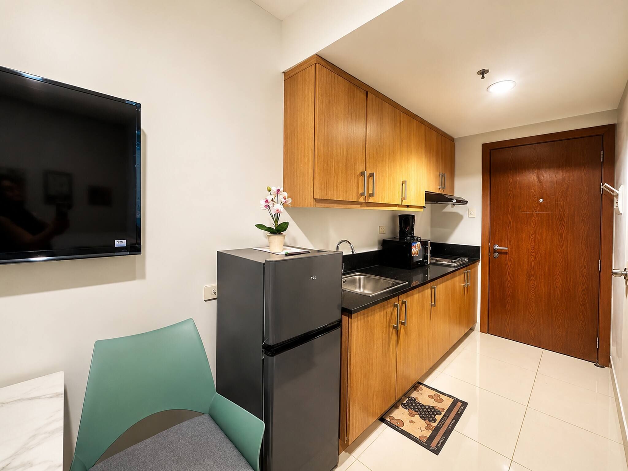 A compact kitchen with wooden cabinets, a black refrigerator, and a black countertop.