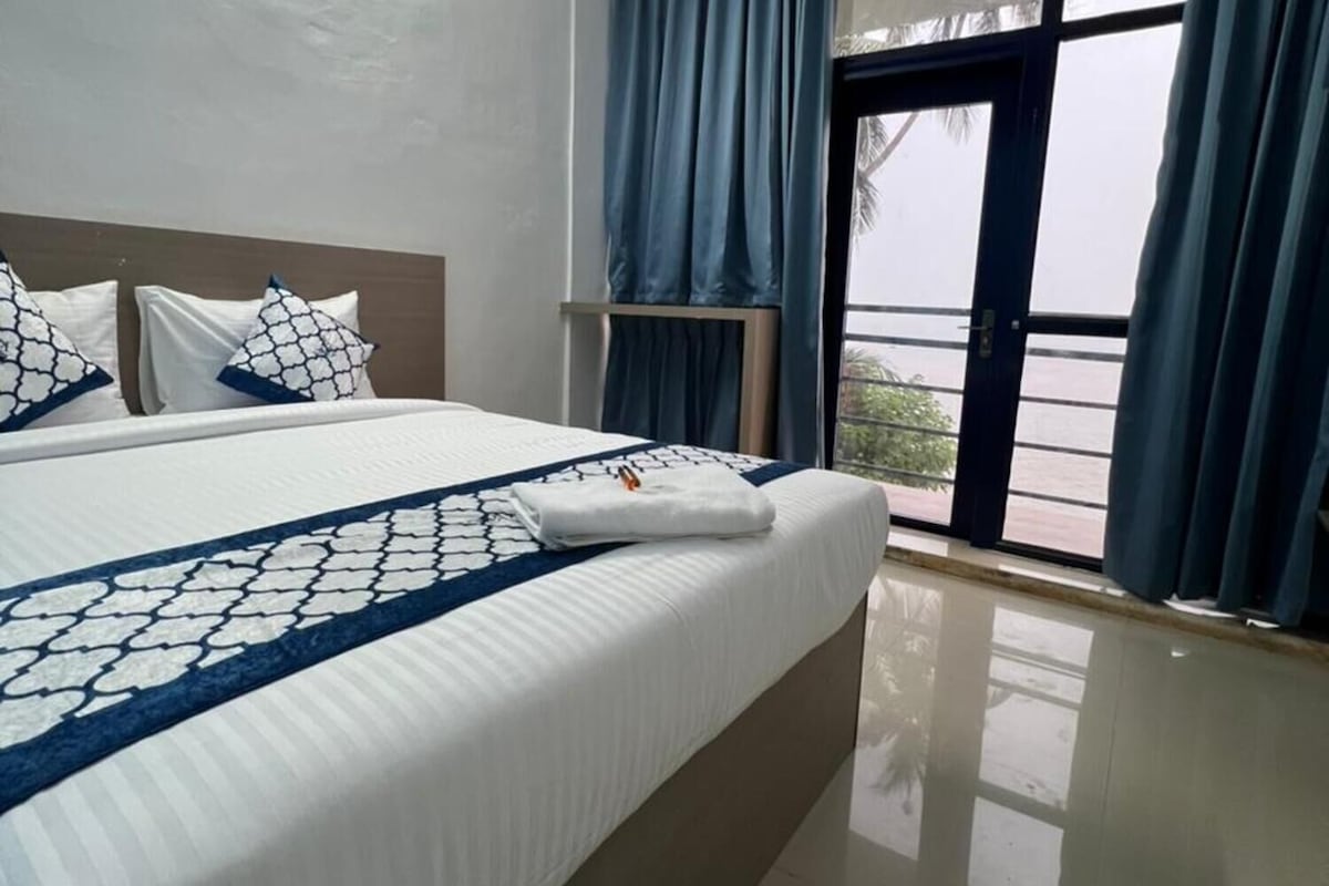 Una habitación de hotel con una cama grande, una ventana con cortinas y vistas al exterior.