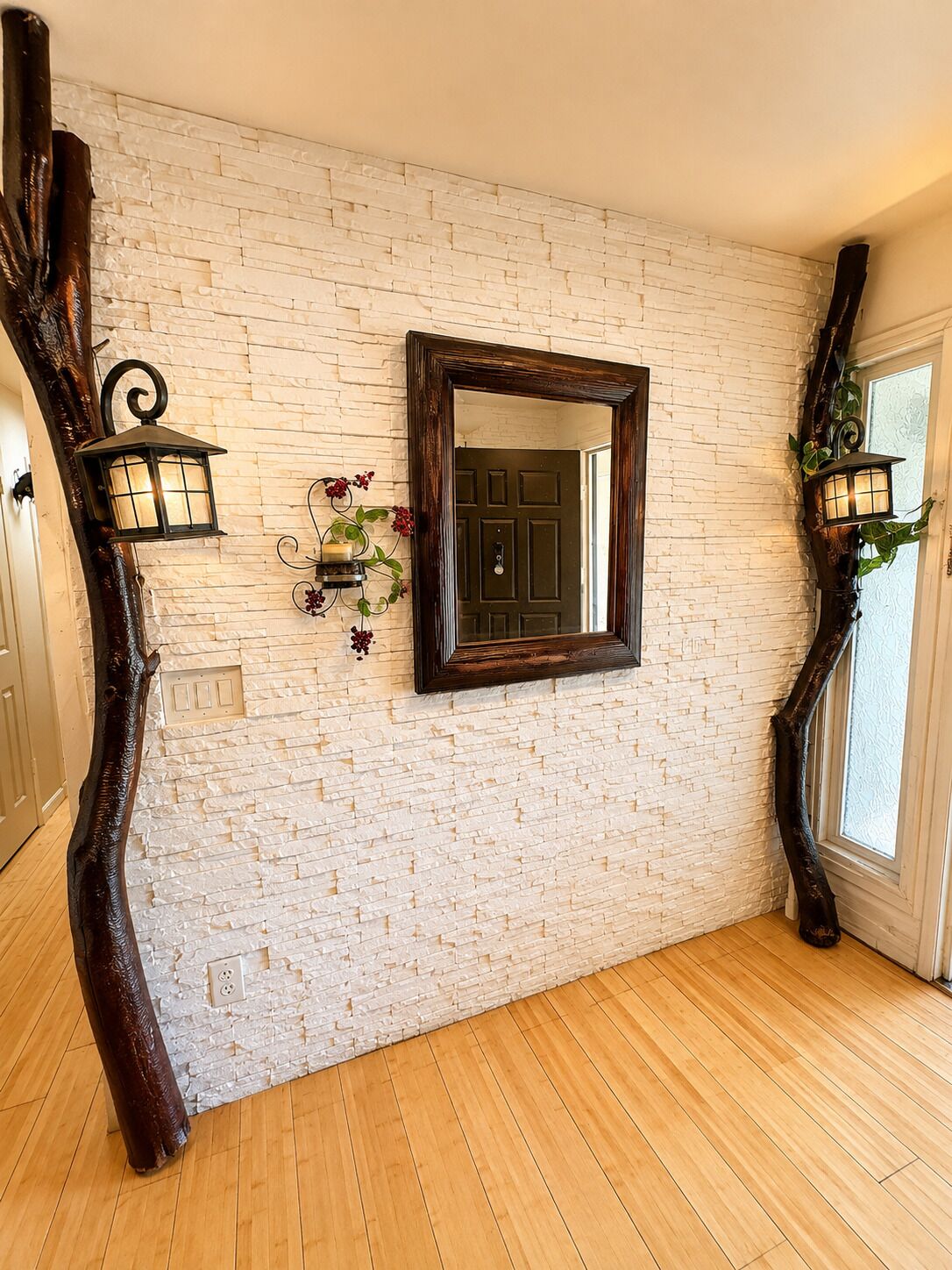 A room with a white brick wall, a wooden floor, a dark wooden door, and two wall-mounted lanterns.