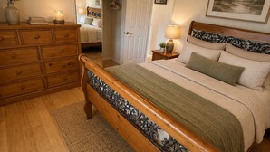 A bedroom with a wooden bed, a dresser, a mirror, a ceiling fan, and a framed picture on the wall.