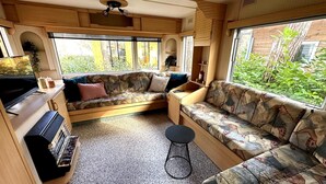 Ein kompaktes Wohnmobil-Interieur mit Küchenzeile, Sitzgelegenheit und großen Fenstern.