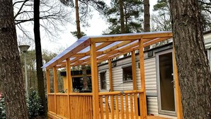 Eine Holzterrasse mit Pergola, umgeben von Bäumen.