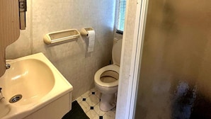 Ein Badezimmer mit Waschbecken, Toilette und einem Fenster mit Jalousien.
