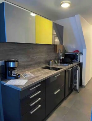 Een moderne keuken met een ingebouwde magnetron, koffiezetapparaat en een spoelbak.