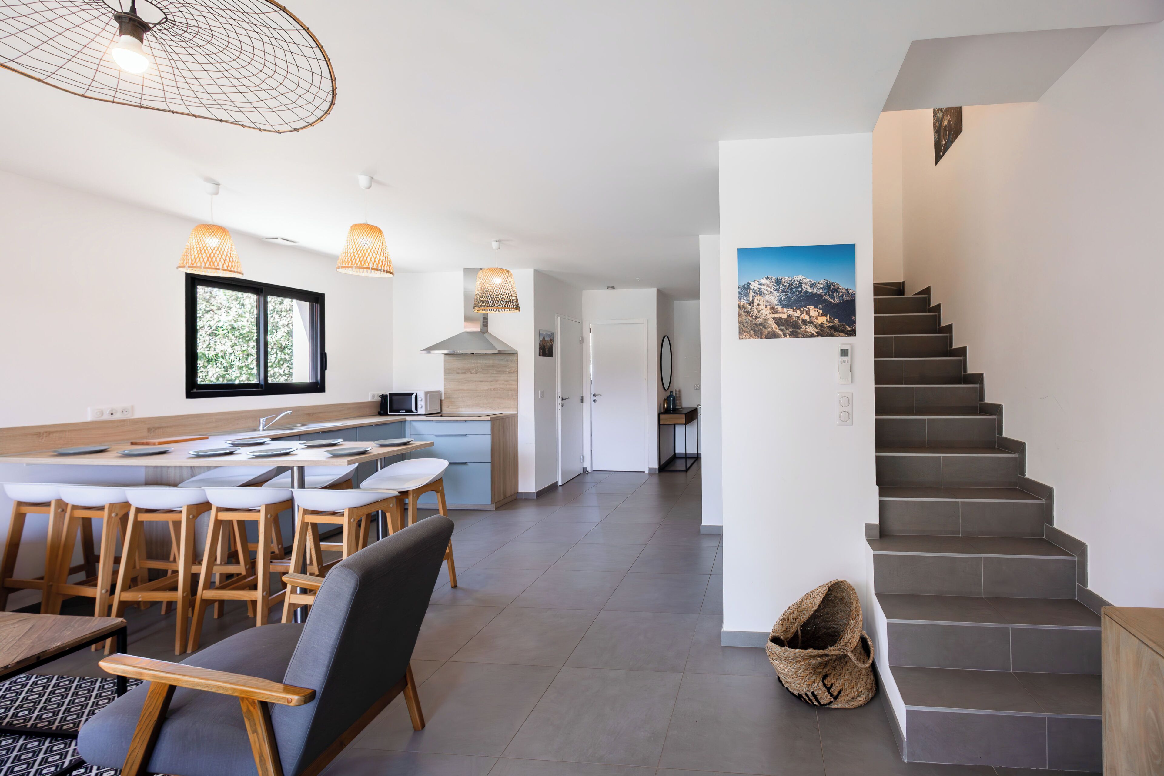 A modern kitchen with a central island, bar stools, and pendant lighting.
