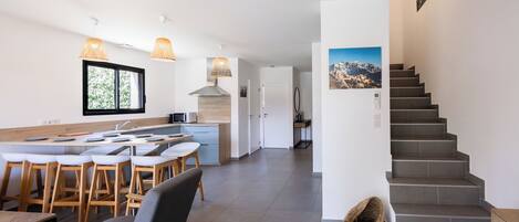 A modern kitchen with a central island, bar stools, and pendant lighting.