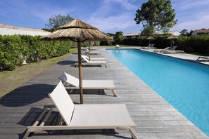 A poolside area with lounge chairs and a thatched umbrella. - Villa - 3 bedrooms - 800 meters from Cala Rossa Beach (Lecci)