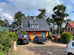 Ein Wohngebiet mit einem zweistöckigen Haus, geparkten Autos und einem Fahrrad.