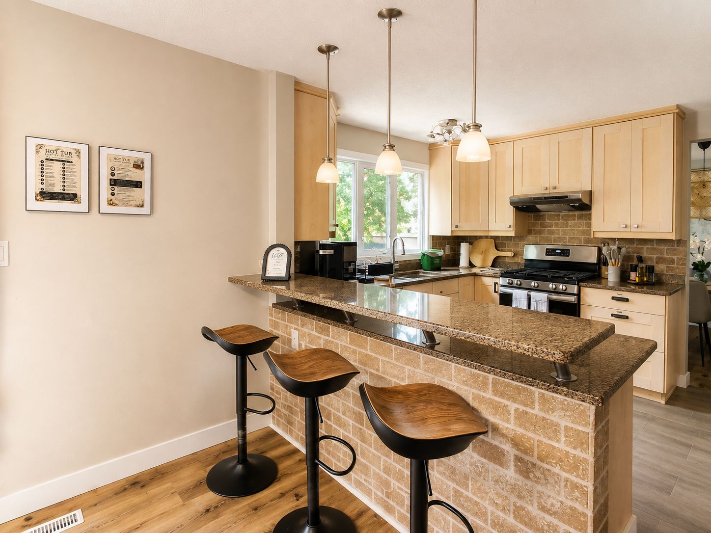 A kitchen with a central island, bar stools, and hanging pendant lights.
